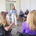 Press 2 Adrien Cotton Speaking To A Group Of Women