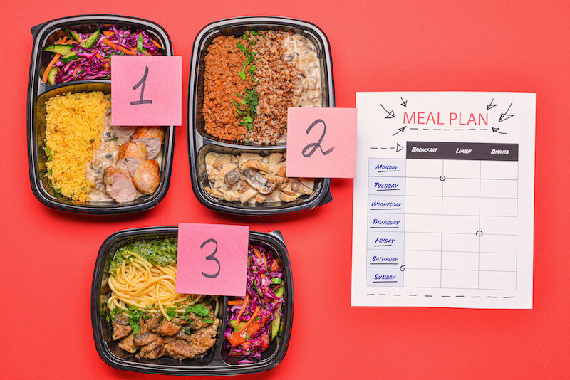 Containers With Healthy Food And Meal Plan On A Red Background