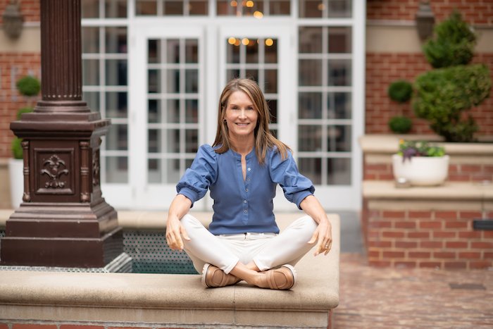 Adrien Cotton Of Alexandria Wellness Sitting Outside Cross Legged By A Fountain