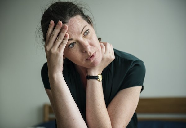 Woman Looks Stressed With Her Head In Her Hand.