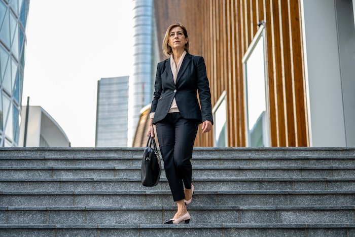 Older Business Woman In A Suit Walking Down The Steps