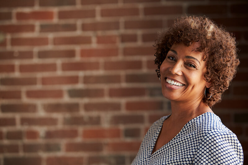 Head And Shoulders Portrait Of Mature Businesswoman In Front Of A Brick Wall.