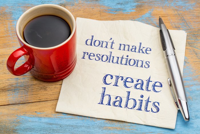 Napkin With &Quot;Don'T Make Resolutions, Create Habits&Quot; Written On It Next To A Pen And A Mug Of Coffee