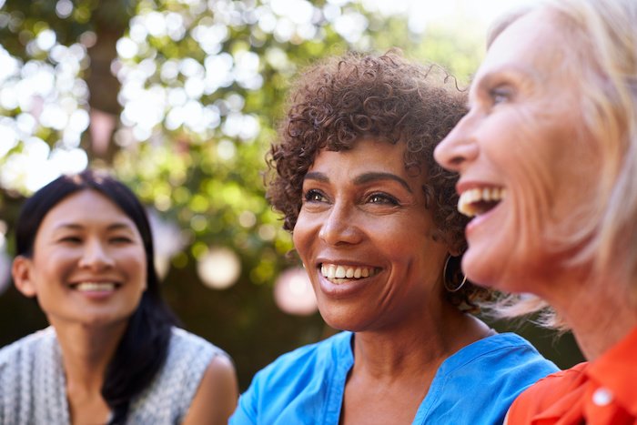 Mature Female Friends Socializing In Backyard Together