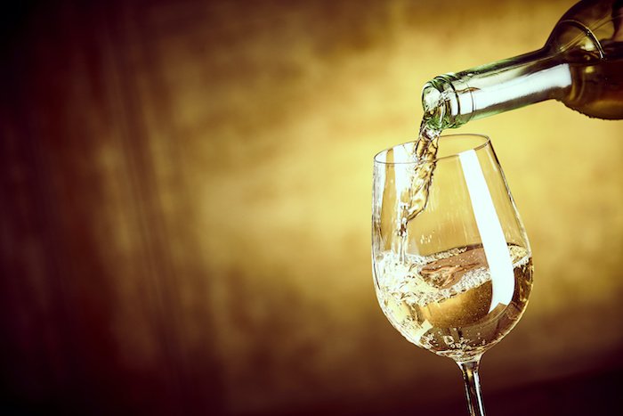 Close Up Of White Wine Being Poured Into A Glass. 