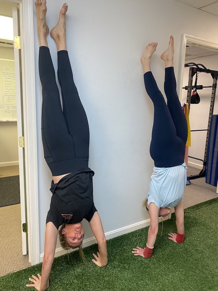 Two People At Alexandria Wellness Doing A Handstand