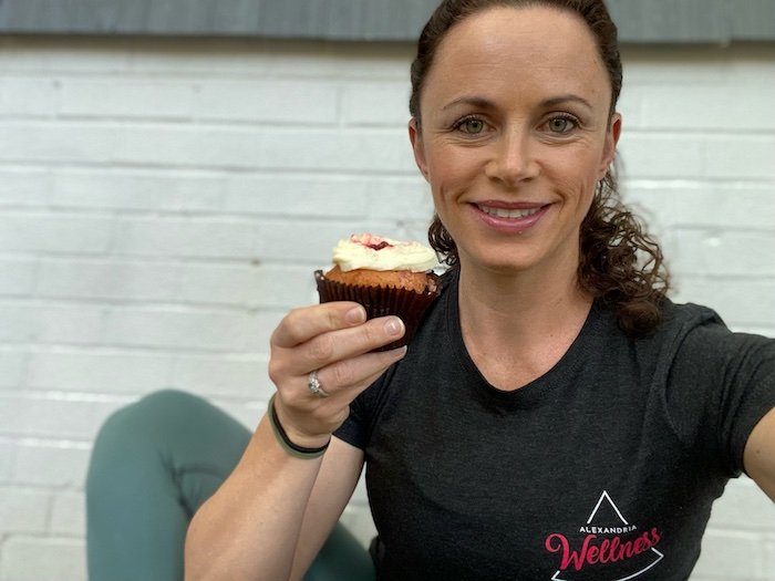Woman holds a cupcake while looking at the camera