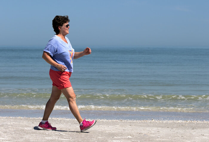 Senior Woman Power Walking On A Gulf Coast Beach.