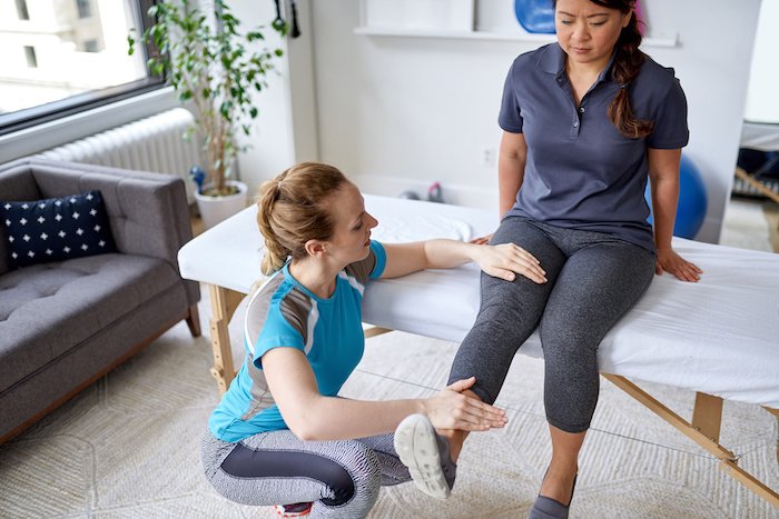 Physical Therapist Works On The Knee Of A Woman On Her Table