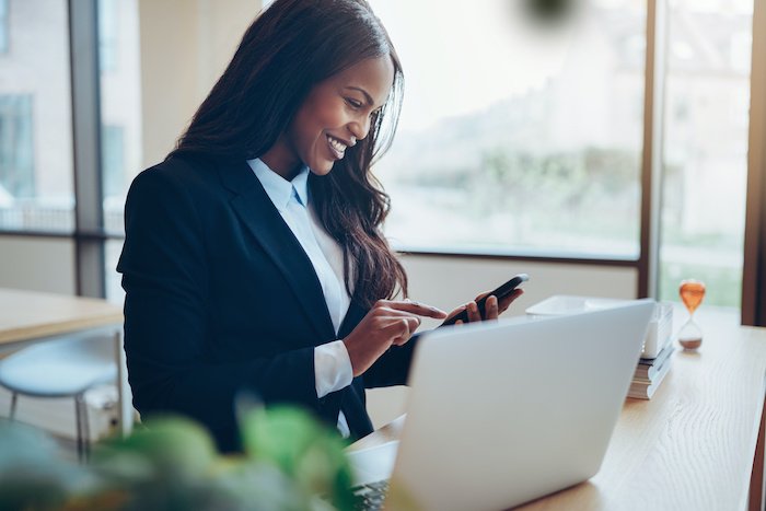 Smiling Black Woman In An Office Looking At A Tablet