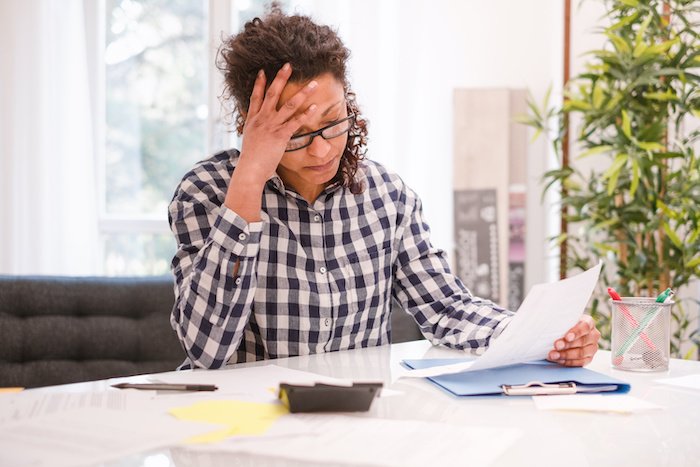 Black Woman Looking Stressed While Looking At Papers On A Desk