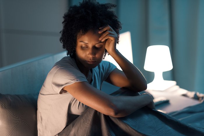 Young Woman Looking Stressed Sits In Her Bed