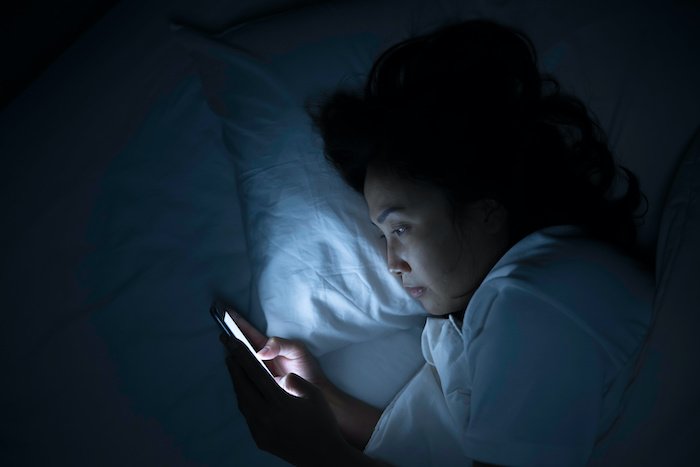 Woman Looking At A Smartphone In Bed In The Dark