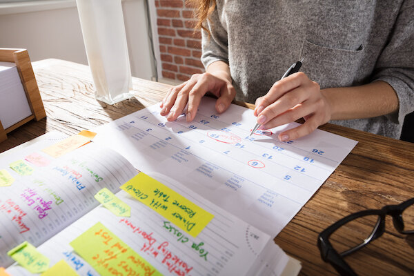 Close-Up Of A Businesswoman Marking Schedule On Calendar 