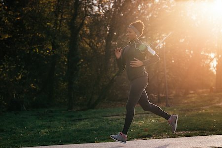 Athletic Black Woman Running In The Park During Sunny Autumn Day