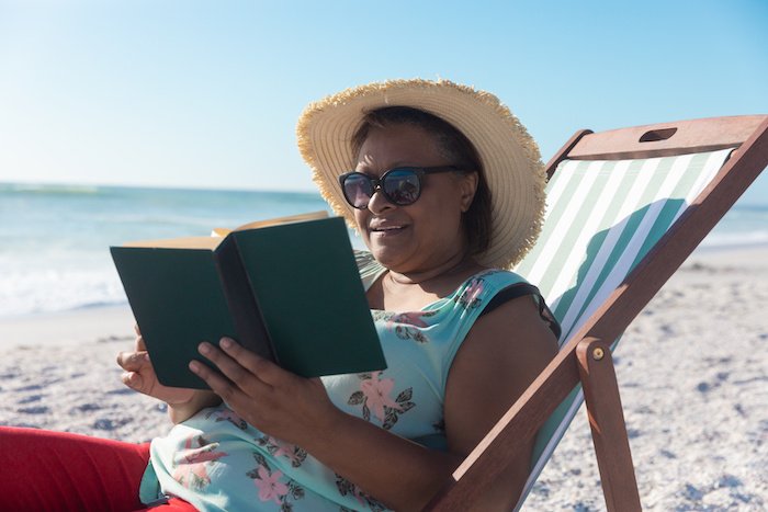 Woman Sits On The Beach With A Book