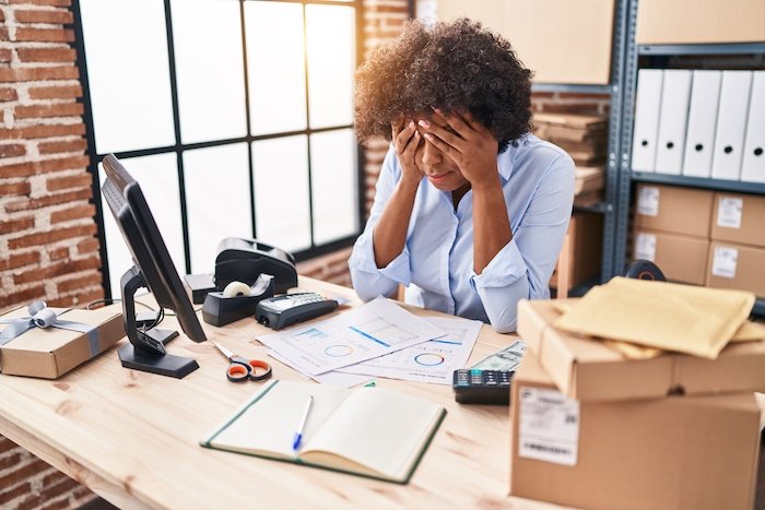 Stressed Woman With Head In Her Hands At A Desk