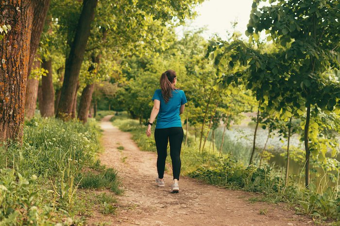 Woman Is Walking On A Path In The Forest On Daytime.