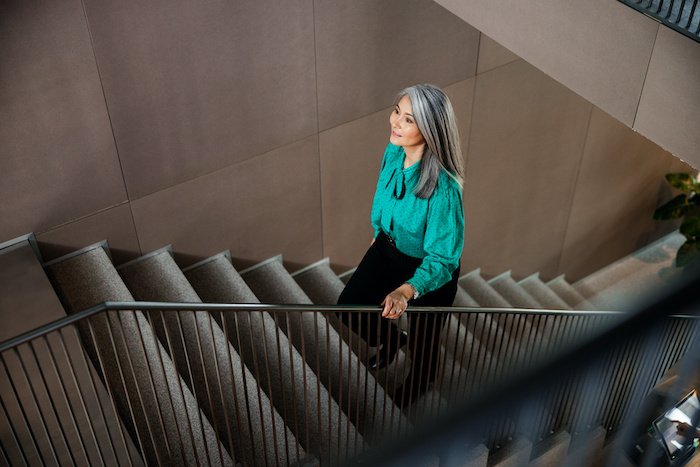 Smiling Elegant Woman In A Green Shirt Walking Up The Stairs