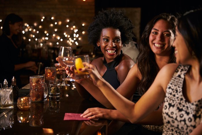 Female Friends Raise Glasses Out At A Restaurant.