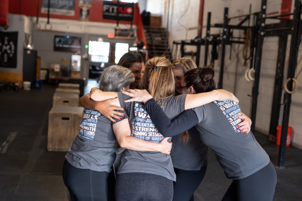Adrien Cotton And A Group Of Women In A Group Hug Showing Back Of Tshirt