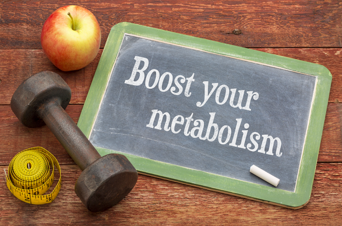 Small Chalkboard With 'Boost Your Metabolism' On It Next To An Apple And A Handweight